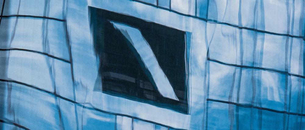 Die Zentrale der Deutschen Bank in Frankfurt am Main spiegelt sich in einer Glasfassade.