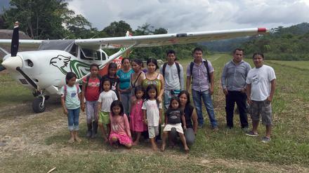 Einige der Bewohner von Sarayaku im ecuadorianischen Amazonasgebiet stehen am unter dem Flügel eines ihrer Flugzeuge.