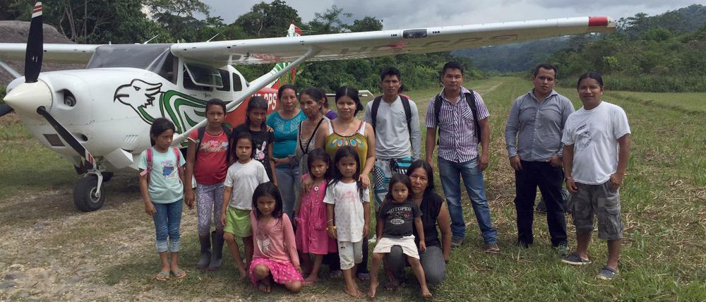 Einige der Bewohner von Sarayaku im ecuadorianischen Amazonasgebiet stehen am unter dem Flügel eines ihrer Flugzeuge.