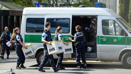 Polizisten tragen bei der Razzia am Mittwoch Pappkartons zu einem Polizeiauto neben einem Porsche-Gebäude. 