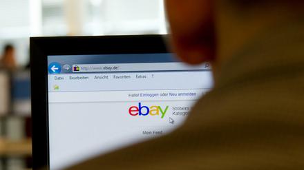 Ein Mann sitzt vor einem Computerbildschirm, auf dem die Ebay-Startseite angezeigt wird.