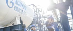 Mitarbeiter stehen an einem Tank, auf dem das Logo der Firma Gazprom zu sehen ist. 
