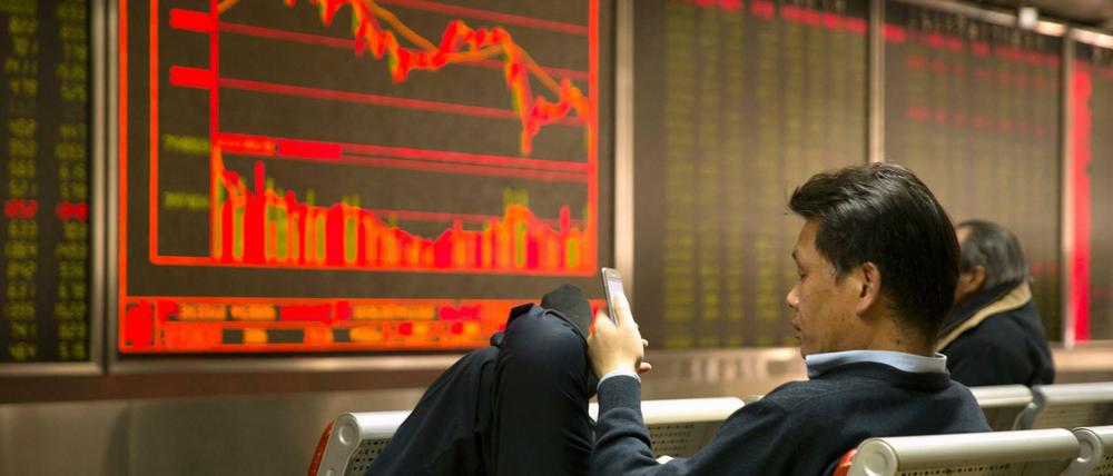 Der Freitag nach Trumps Strafzoll-Beschlüssen blickt ein chinesischer Investor auf sein Smartphone, während er in einem Brokerhaus die Börsenpreise verfolgt.