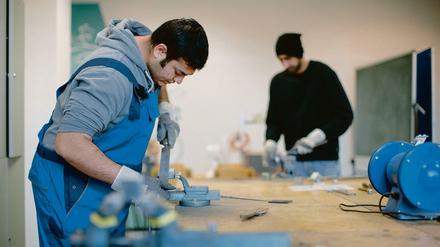 Der afghanische Flüchtling Sha Kah Ahmadi (l.) und der indische Flüchtling Singh Satwinder feilen in der Fortbildungsakademie der Wirtschaft (FAW) in Dresden (Sachen) an Metallwerkstücken. Beide sind zum Probearbeiten da, um deren Kompetenzen auszuloten. 