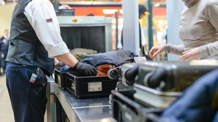 Ein Mitarbeiter eines Sicherheitsdienstleisters kontrolliert Handgepäck im Sicherheitsbereich am Flughafen Tegel.