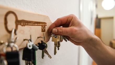 Ein Mann hängt einen Schlüsselbund an einen Haken am Schlüsselbrett.