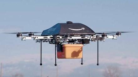 Zustellung ohne Bote. Für Amazon liegt die Zukunft der Logistik in der Luft. Der „Octocopter“, so genannt wegen der acht Motoren, trägt das Logo des Konzerns. Der geschwungene Pfeil soll ein Lächeln symbolisieren. Unten hängt eine gelbe Box für die bestellte Ware. Foto: dpa