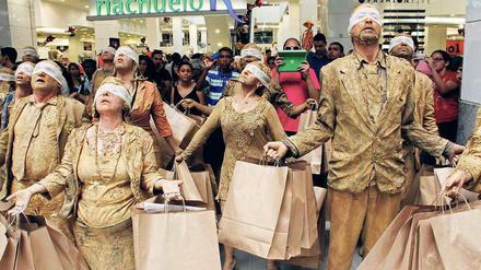 Eine Gruppe von Kunststudenten protestiert in einem Kaufhaus in Brasilien gegen Konsumverzicht. Sie sind mit brauner Farbe beschmiert und tragen braune Papiertüten.