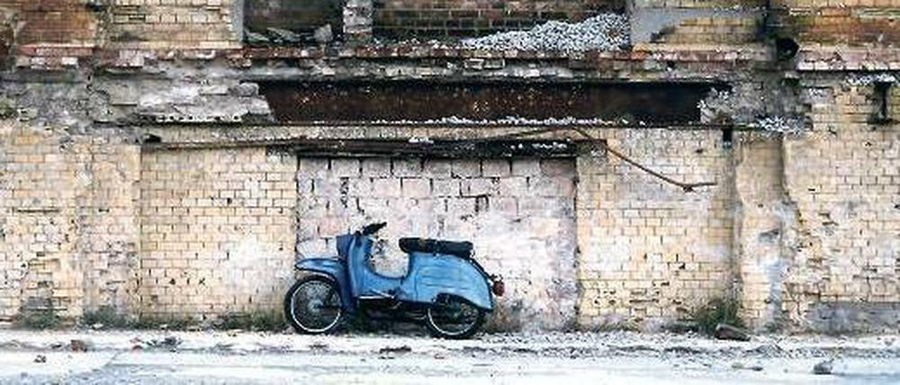 Ein blauer Simson-Motorroller steht vor einer Ruine.