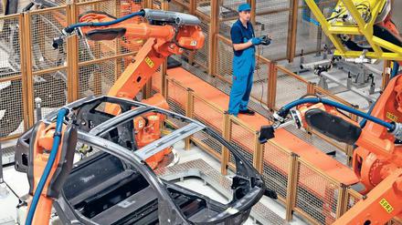 Suchbild. Menschen sind in der Karosseriebau-Halle des Leipziger BMW-Werks kaum zu finden. Es dominieren die Greifarme der Kuka-Roboter, die Leichtbauteile zusammenfügen. Die Mitarbeiter kontrollieren nur noch die Produktion der Elektroautos. Foto: Woitas/dpa