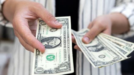 Eine Frau hält Dollar-Scheine in der Hand.