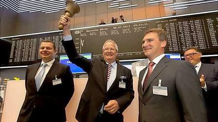 Osram Vorstandsvorsitzender Wolfgang Dehen und sein Finanzchef Klaus Patzak stehen mit zwei weiteren Männern auf dem Frankfurter Börsenparkett vor der Anzeigetafel. Dehen hält die Glocke hoch.
