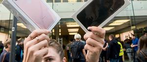 Eine Frau präsentiert zum Verkaufsstart des neuen iPhone 7 zwei Smartphones.