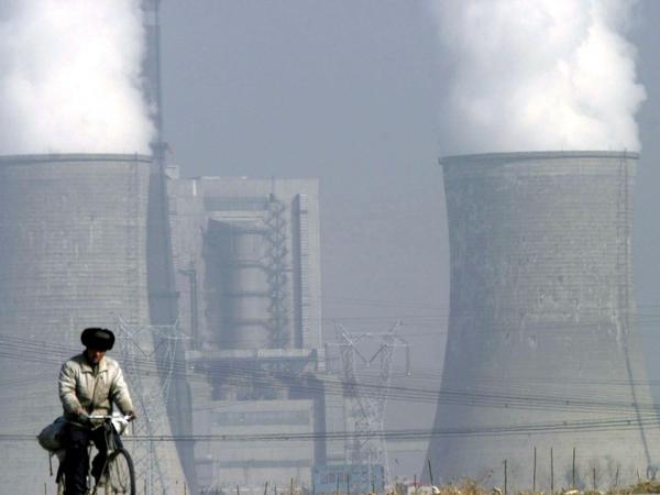 Ein Mann fährt in Shuozhou, China, nahe der Kühltürme des Kohlekraftwerks Shengtou entlang (Archivfoto).
