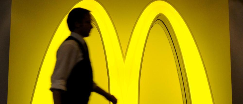 Ein Mann geht am am Logo der Fast-Food-Kette McDonald's vorbei. 