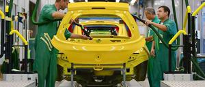 Bei Opel in Eisenach arbeiten Männer in grünen Overalls an einem Kleinwagen, der gelb lackeirt ist. 