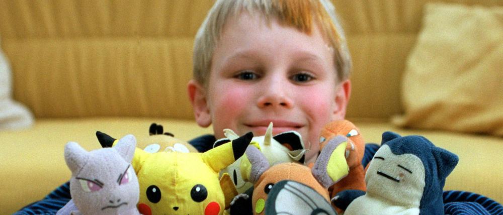 Ein Kind posiert mit seinen Pokemon-Figuren.