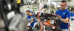 Ein VW-Mitarbeiter befestigt im Werk in Wolfsburg ein Bauteil am Motorblock für den Hybrid-Golf.