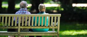 Zwei Rentner sitzen im Schatten des Schlossparks Charlottenburg auf einer Bank.