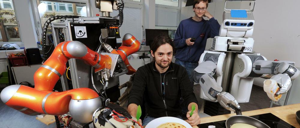 Küchenhilfe. Die Roboter Rosie (l.) und James (r.) servieren den Doktoranden Ingo Kresse (2.v.r.) und Thomas Rühr (2.v.l.) an der Technischen Universität München Pfannkuchen. 