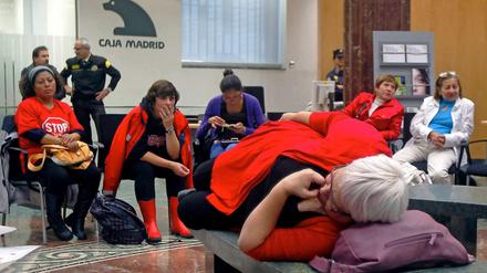 Aus Protest gegen die Zwangsräumung ihrer Häuser haben diese spanischen Frauen eine Bank besetzt.