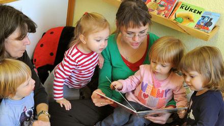 In einer Leipziger Kindertagesstätte schauen die Kinder mit einer Logopädin und einer Erzieherin Bücher an.