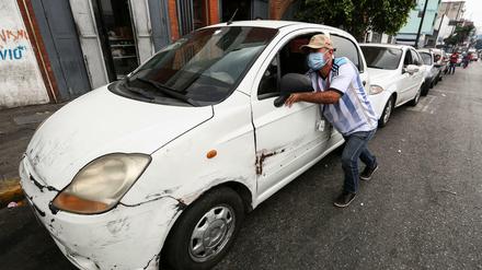 Ein Mann in Venezuela schiebt sein Auto zu einer Tankstelle.