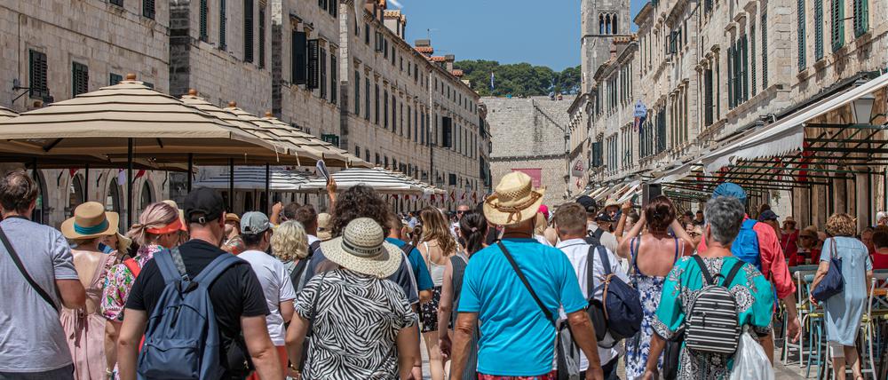 Touristen gehen durch eine Straße von Dubrovnik. Dubrovnik ist bei Touristen sehr beliebt.