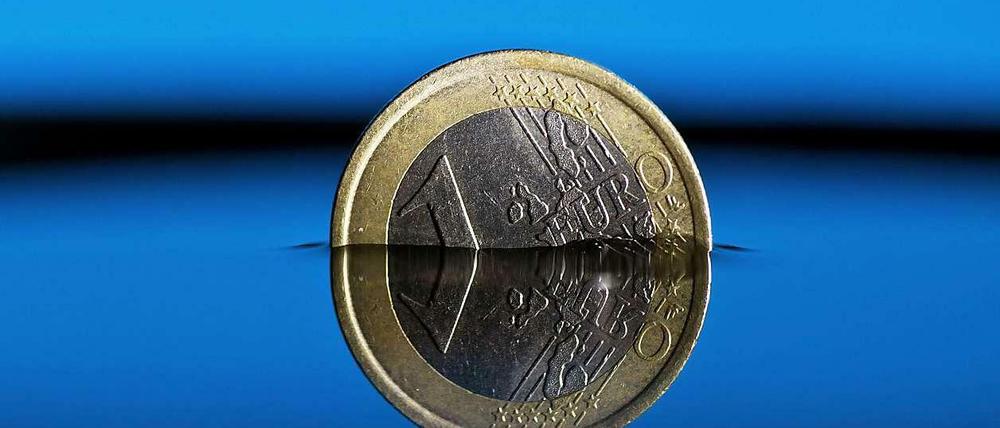 Eine Ein-Euro-Münze steht zur Hälfte im Wasser.