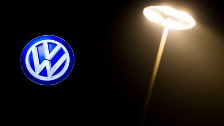 Das Volkswagen-Logo leuchtet an einem Werksgebäude. 