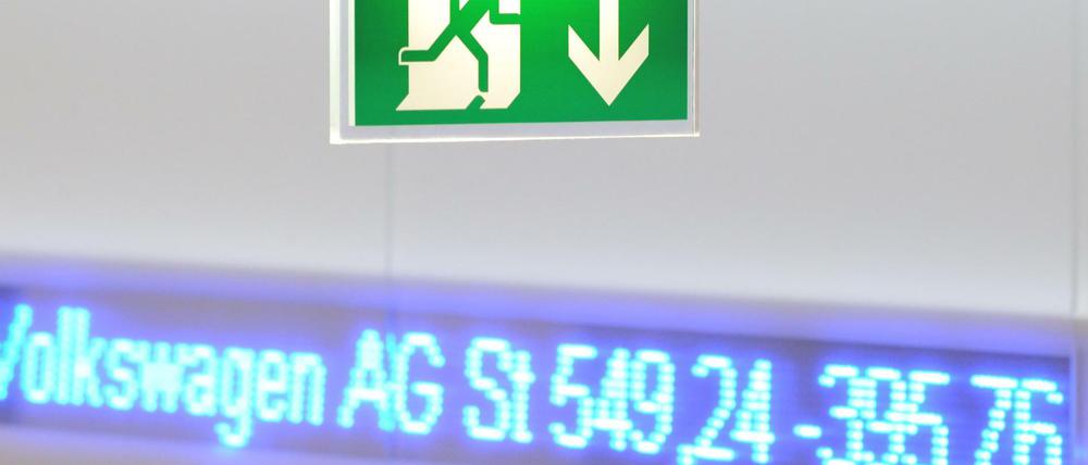 Ein Hinweisschild für einen Notausgang ist in der Börse in Frankfurt am Main vor einem elektronischen Laufband mit dem DAX-Wert von Volkswagen zu sehen.