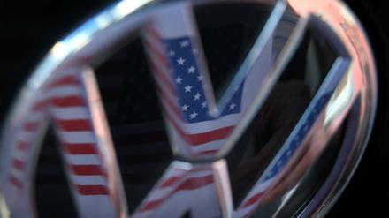 Eine US-amerikanische Flagge spiegelt sich im Logo eines Volkswagens. 