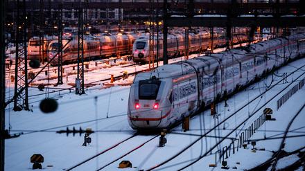 Mehrere ICE der Deutschen Bahn stehen auf verschneiten Abstellgleisen vor dem Hauptbahnhof.