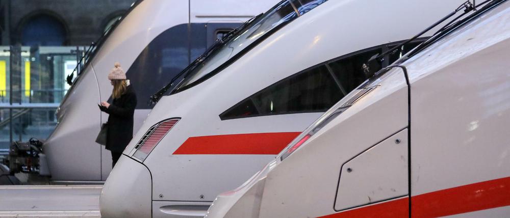 Eine Reisende wartet zwischen zwei ICE Fernzügen und einer Regionalbahn auf einem Bahnsteig im Hauptbahnhof Leipzig. 