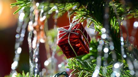 Ein kleines rotes Geschenkpaket als Weihnachtsbaumanhänger und Lametta
