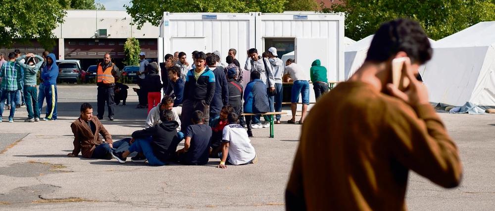 Junge Männer warten vor einem Container des Landesamtes für Gesundheit und Soziales um sich auf dem Gelände der Flüchtlingsunterkunft in der ehemaligen Schmidt-Knobelsdorf-Kaserne in Berlin registrieren zu lassen. 