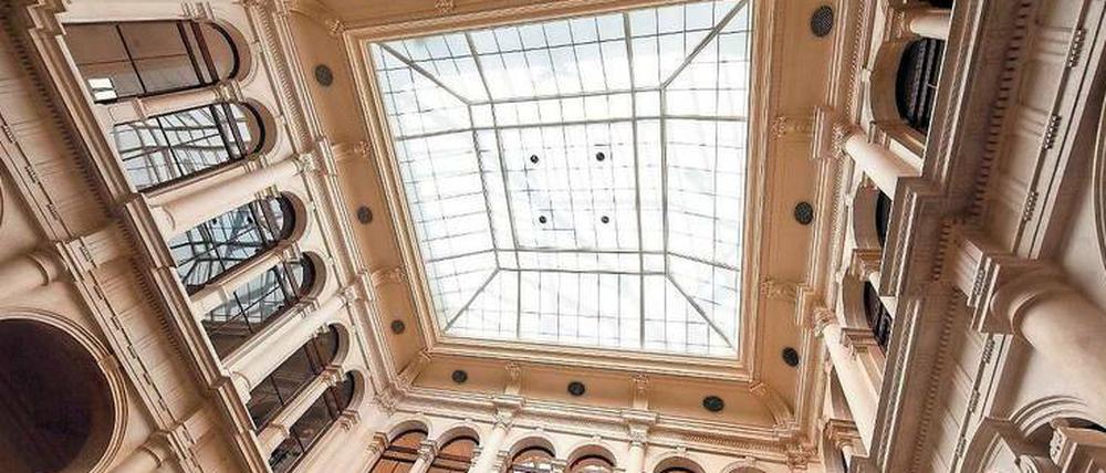 Durch das gläserne Kuppeldach flutet Licht in die ehemalige Säulenschalterhalle, die sich über zwei Geschosse erstreckt. 