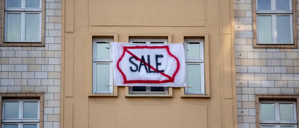 Ein Plakat gegen den Verkauf von Mietwohnungen an die Deutsche Wohnen SE an einer Gebäudefassade in der Karl-Marx-Allee. 