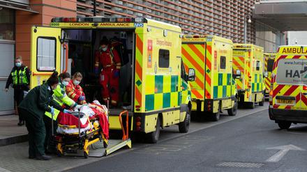 Eine Reihe von Krankenwagen vor einem Krankenhaus in England. Notärzte kümmern sich um einen neu angekommenen Patienten.  
