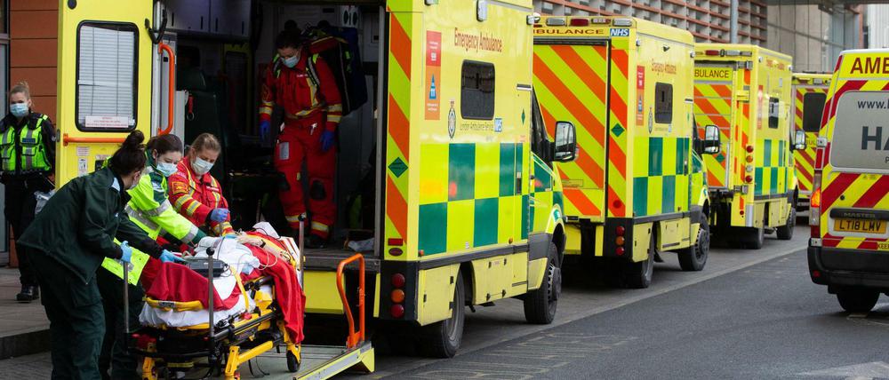 Eine Reihe von Krankenwagen vor einem Krankenhaus in England. Notärzte kümmern sich um einen neu angekommenen Patienten.  