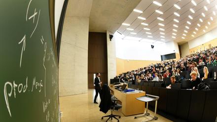 Ein Dozent steht vor Studierenden in einem Hörsaal.