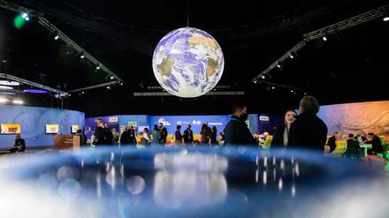 ARCHIV - 13.11.2021, Großbritannien, Glasgow: Menschen stehen bei der UN-Klimakonferenz COP26 unter einem Globus.  (zu dpa "Sturgeon: Keine Anzeichen für Corona-Ausbrüche bei Klimagipfel") Foto: Christoph Soeder/dpa +++ dpa-Bildfunk +++