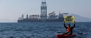 Ein Greenpeace-Aktivist hält ein Schild in die Höhe – im Hintergrund das Tiefsee-Bergbauschiff Hidden Gem (Symbolbild)