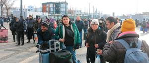 Fünf junge Männer und Frauen stehen mit ihren Koffern vor einem Bahnhofsgebäude.