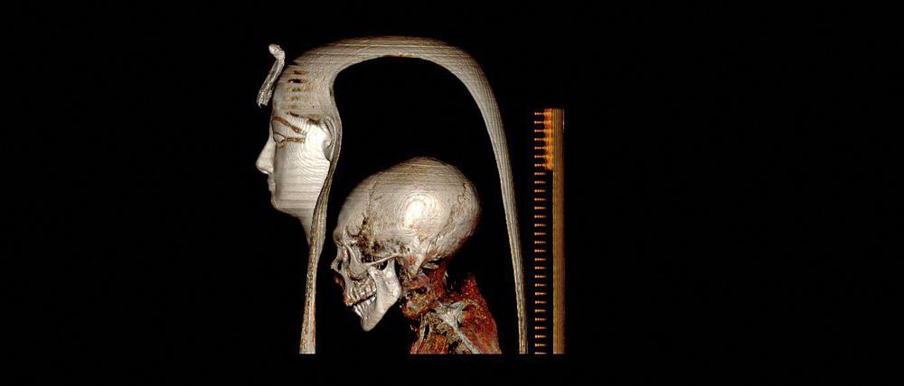 Hinter einer ägyptischen Totenmaske ist der Schädel eines Menschen zu sehen.