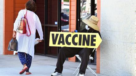 Nachlassender Impfwille in den USA: Eine Frau läuft an einem Mitarbeiter vorbei, der auf ein Impfzentrum aufmerksam macht.
