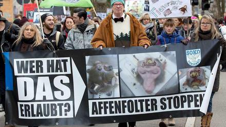 Menschen halten auf einer Demonstration Plakate mit Affenköpfen in Versuchsapparaturen und mit Aufschriften wie "Affenfolter stoppen".