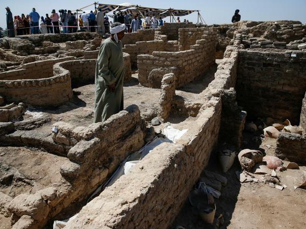 Ein Ägypter steht inmitten ausgegrabener Fundamente einer altägyptischen Stadt.