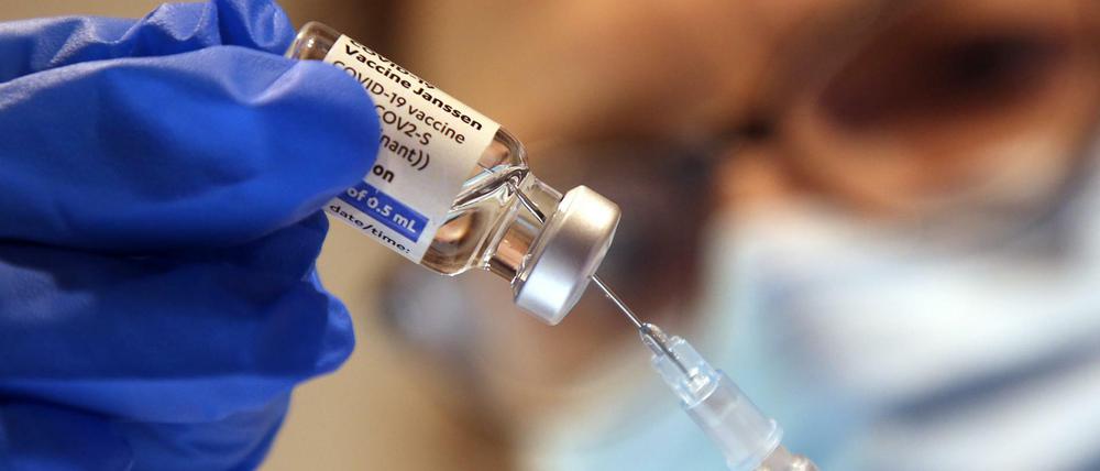 Eine Arzthelferin zieht eine Spritze mit einem Corona-Impfstoff aus.