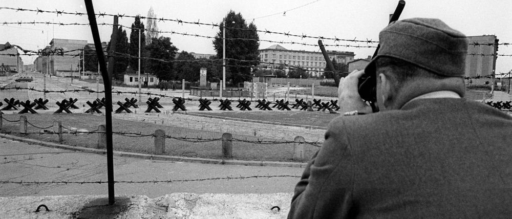 Gefährlicher Grenzstreifen. Ein Wachposten beobachtet den Grenzstreifen der Berliner Mauer am Potsdamer Platz, Personen (1961).